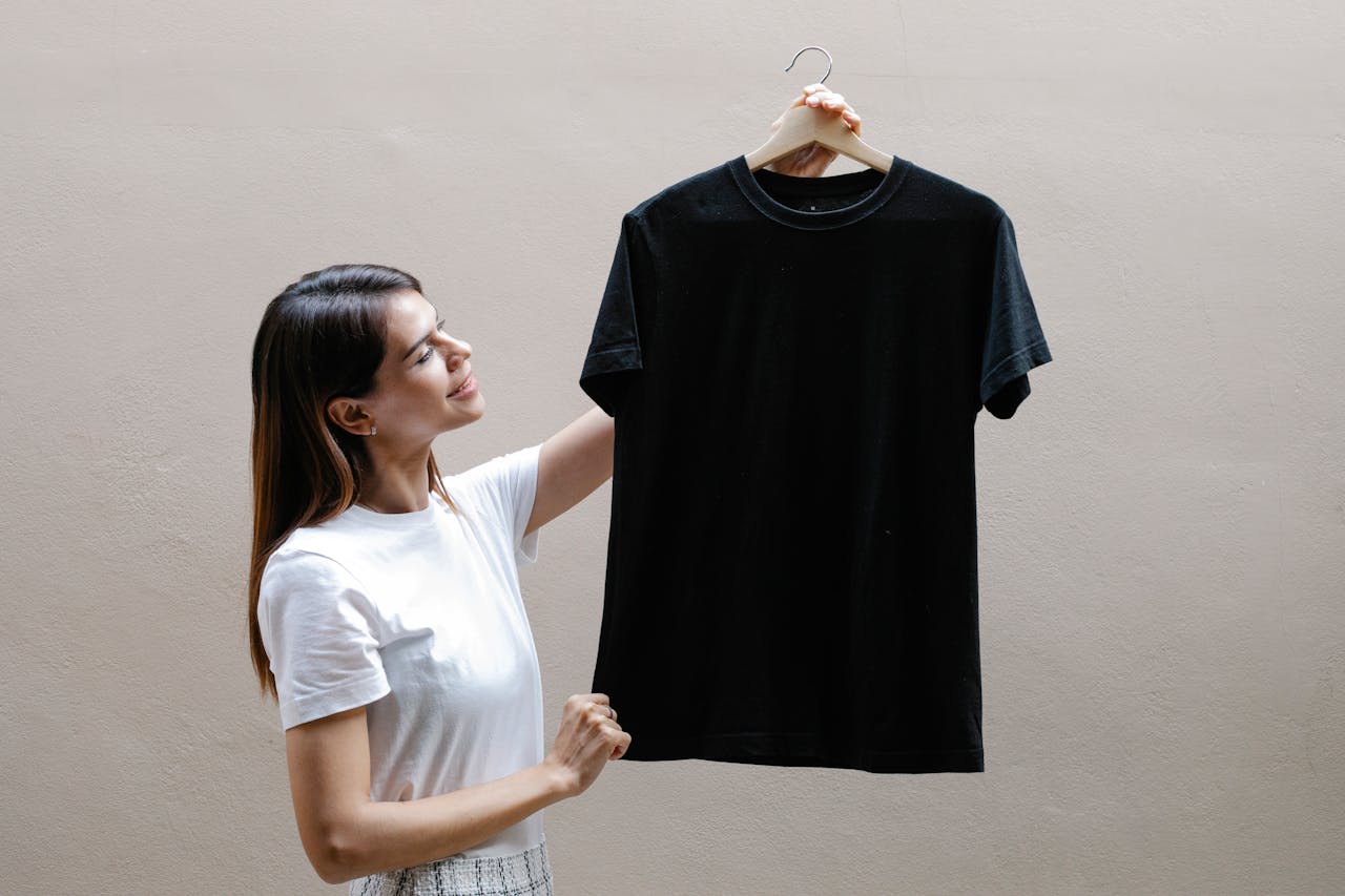 Mulher a segurar uma t-shirt preta num cabide
